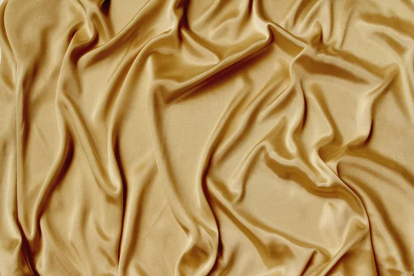 Oro hermosa tela de satén cubierta con pliegues suaves, fondo de tela de seda, primer plano, espacio de copia — Foto de Stock