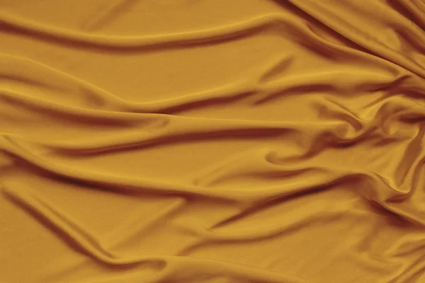 Ouro bonito tecido de cetim drapeado com dobras macias, fundo de pano de seda, close-up, espaço de cópia — Fotografia de Stock