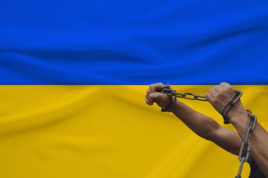 devlet bayrağının arka planına karşı kalın bir demir çar sarılmış kaslı erkek elleri, siyasi mücadele kavramı, suç, zulüm, hapis, insan özgürlüğünün ihlali