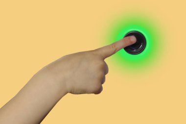 çocuğun el bir işaret parmağı ile yeşil ışık ile düğmeye basar, sarı bir arka plan, fotoğraf, kavram, yakın çekim, kopyalama alanı izole
