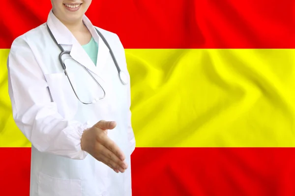 Junge schöne Ärztin mit einem offenen Lächeln reicht seine Hand zur Begrüßung auf dem Hintergrund der Nationalflagge, Konzepte des Gesundheitswesens, der Medizin — Stockfoto