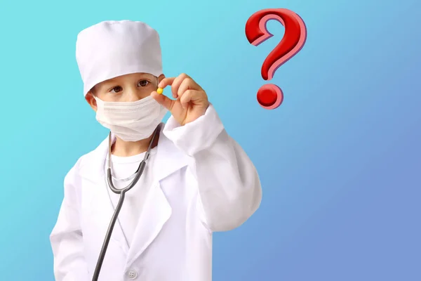 Мальчик в белом медицинском костюме держит желтую таблетку в руках, большой вопросительный знак, изолировать — стоковое фото