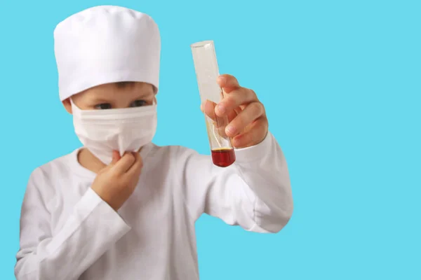Menino em um terno médico branco detém um tubo de teste de laboratório de vidro em suas mãos, isolar — Fotografia de Stock