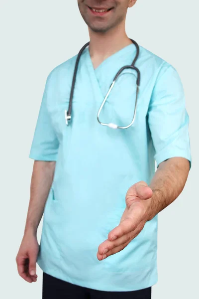 Boynunda bir stetoskop ile mavi üniformalı profesyonel giysiler erkek doktor beyaz bir arka plan, tıbbi kavram, yakın çekim, kopya alanı tebrik için elini uzatır — Stok fotoğraf