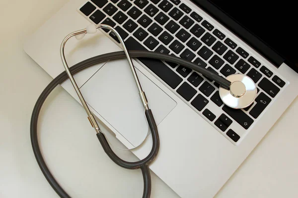 Estetoscópio médico em um teclado portátil preto — Fotografia de Stock