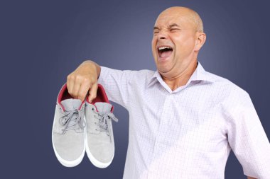 açık gömlekli bir adam elinde gri erkek mokasen bir çift tutar ve çığlıklar, yüzünde bir grimace, yakın çekim, kopya alanı