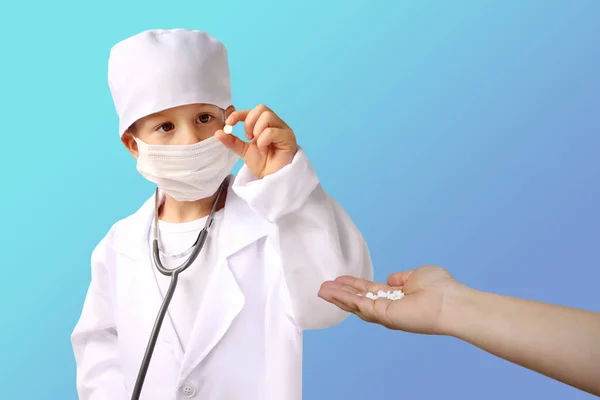 Хлопчик у білому медичному костюмі тримає білу таблетку в руках, жіноча рука тримає жменьку білих таблеток, ізольовані — стокове фото