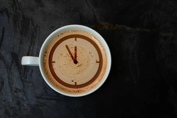 Copo branco com cappuccino e espuma na forma de um mostrador padrão relógio, vista superior, close-up, espaço de cópia — Fotografia de Stock