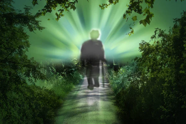 parlak ışık gidiyor bir ormanda bir yolda yaşlı bir adamın bulanık siluet. Ölüm kavramı, ölümden sonra yaşam, geçiş, cennet, intihar, depresyon, yaşlı insanların ruh sağlığı sorunları