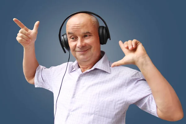 Positive man in headphones on a dark background, musical concept, learning a foreign language, horizontal, close-up, copy space — Stock Photo, Image