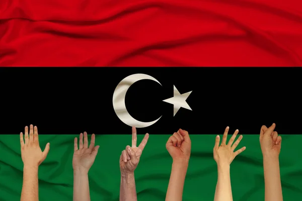 Wiele rąk podniesionych na tle flagi narodowej Libii na delikatnym błyszczącym jedwabiu z miękkimi draperiach, pojęcie ludności kraju, jedność, poziome, zbliżenie, przestrzeń kopiowania — Zdjęcie stockowe