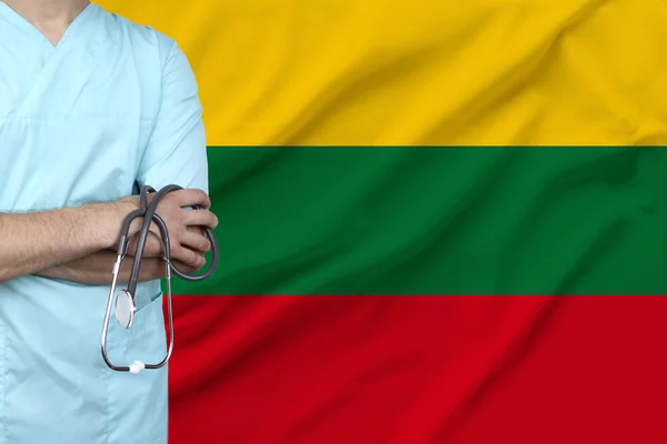 partial photograph of a doctor in uniform against the background of the national flag of Lithuania on delicate shiny silk, the concept of medical care and insurance in the country, close-up, copy spac