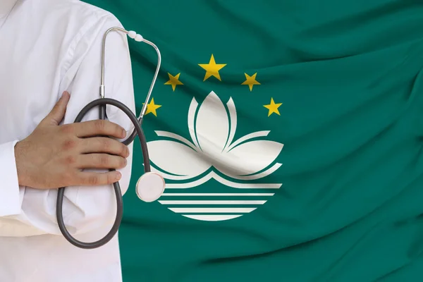 partial photograph of the doctor in uniform against the background of the Macau national flag on delicate shiny silk, the concept of medical care and insurance in the country, close-up, copy space