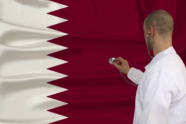 partial photograph of a doctor in uniform against the background of the national flag of Qatar on delicate shiny silk with soft draperies, the concept of medical care and insurance in the country