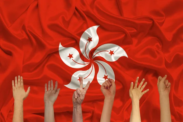 Many hands raised up against the background of the national flag of Hong Kong on delicate shiny silk, concept of the country's population, unity, horizontal, close-up, copy space — Stock Photo, Image