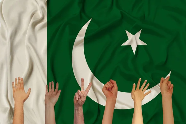 Many hands raised up against the background of the national flag of Pakistan on delicate shiny silk, concept of the country's population, unity, horizontal, close-up, copy space — Stock Photo, Image