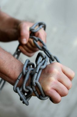 erkeklerin elleri büyük bir demir zincir sarılmış, onları kırmaya çalışıyor, esaret kavramı, mücadele, yer kazanmak, yakın çekim