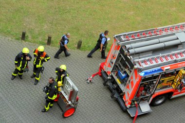 Frankfurt, Almanya, Haziran 2019: Parlak sarı üniformalı bir ekip parlak kırmızı servis itfaiye aracının yanında duruyor, iki polis baypas taşımacılığı