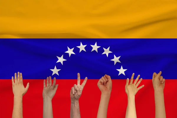 Veel verhoogde handen van mensen tegen de achtergrond van een gekleurde zijde staat vlag met zachte plooien, People Unity concept — Stockfoto
