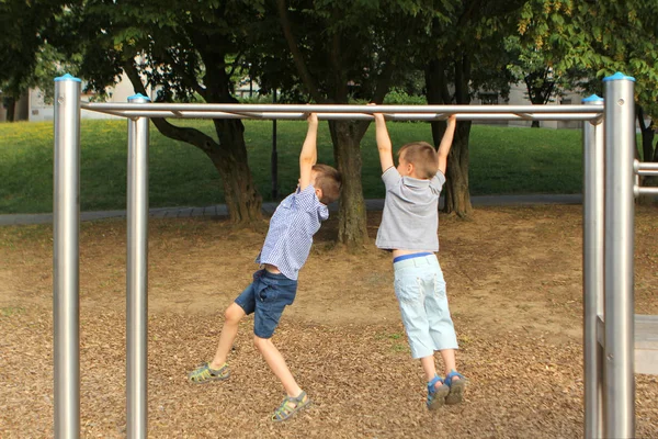 Dois meninos em shorts subir em equipamentos esportivos no parque no verão, trem, coordenar, equilíbrio, corpo — Fotografia de Stock