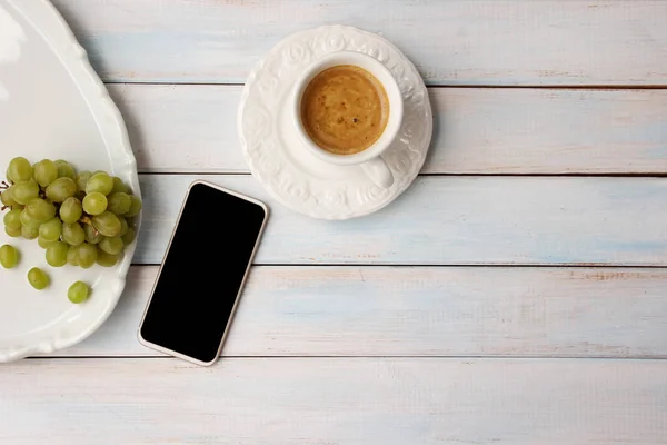 스마트 폰의 텍스트에 대한 검은 색 공백과 커피가있는 흰색 컵, 접시에 포도, 개념 아침, 상단보기, 복사 공간 — 스톡 사진
