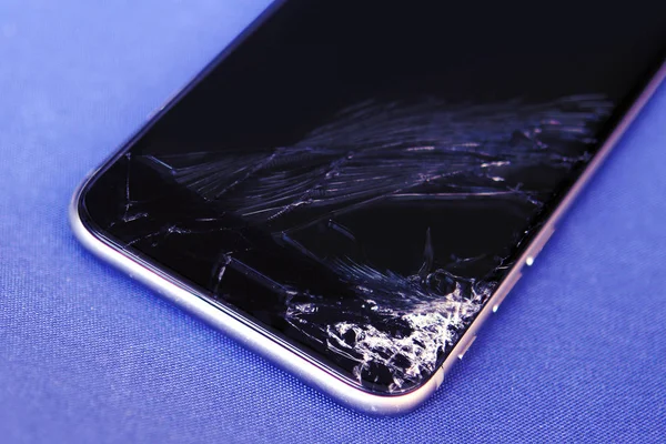 Teléfono móvil roto sobre un fondo azul con tintado azul — Foto de Stock