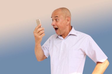 aptal bir görünüm ile hafif bir gömlek komik adam, onun akıllı telefon, teknoloji kavramı, yatay, yakın çekim, kopya alanı ağzını açarak