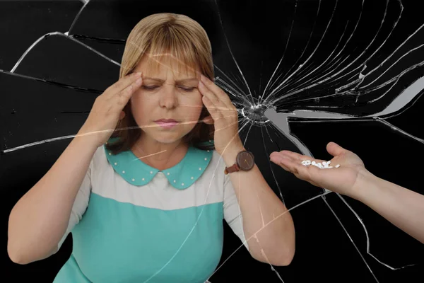 Mooie middelbare leeftijd vrouw die houdt beide handen op haar hoofd, zwarte achtergrond van gebroken glas, vrouwelijke hand houdt uit een handvol witte pillen, close-up, kopieer ruimte — Stockfoto