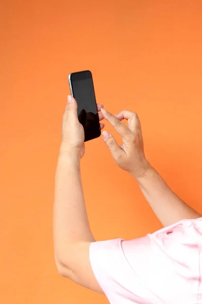 Mujer sosteniendo un teléfono, fondo naranja, primer plano, espacio para copiar —  Fotos de Stock