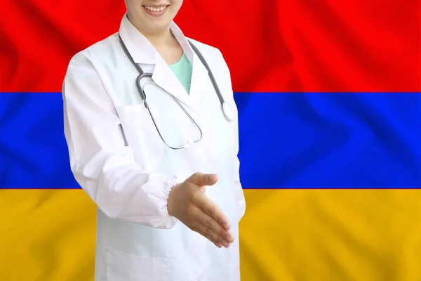 Young beautiful girl doctor with an open smile holds out his hand for greeting on the background of the national flag, concepts of health care, medicine in — Stock Photo, Image