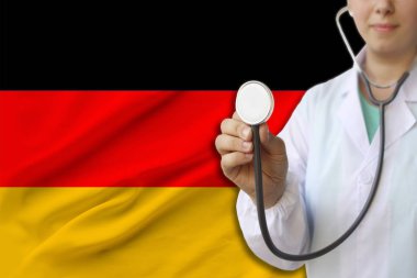bir kız doktor kısmi fotoğraf, Almanya devletinin ulusal bayrağının arka planına karşı üniformalı bir hemşire, ülkede tıbbi bakım ve sigorta kavramı