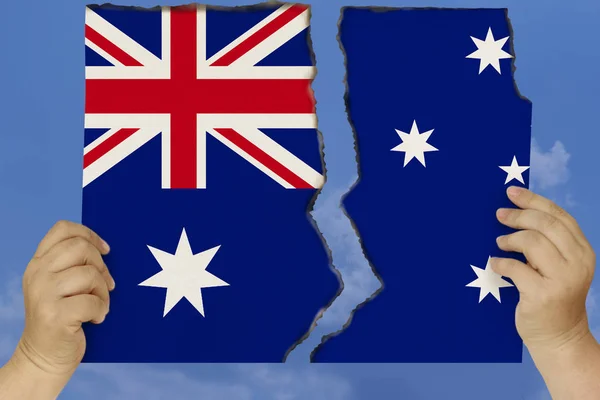 Mujer sostiene en ambas manos contra un cielo azul desgarrado en dos cartón con bordes chamuscados que representan la bandera nacional de Australia, el concepto de una crisis de estado, la renuncia a la ciudadanía, la destrucción — Foto de Stock