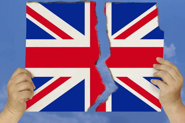 Femme tient dans les deux mains contre un ciel bleu déchiré en deux cartons avec des bords poêlés à l'image du drapeau national de Grande-Bretagne, concept de crise d'Etat, renonciation à la citoyenneté, destruc — Photo