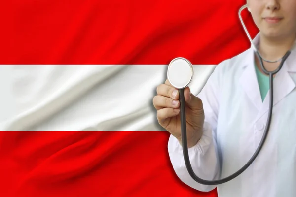 Fotografía parcial de una doctora, enfermera con un estetoscopio en uniforme en el fondo de la bandera nacional del estado de Austria, el concepto de atención médica y seguro en el país — Foto de Stock