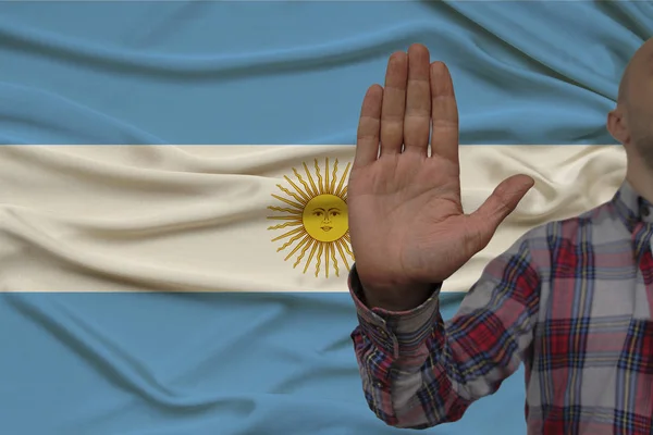 Mano masculina con un gesto de protesta, juramentos contra el telón de fondo de una bandera nacional de seda, el concepto de negación y prohibición y prohibición, primer plano, espacio para copiar — Foto de Stock