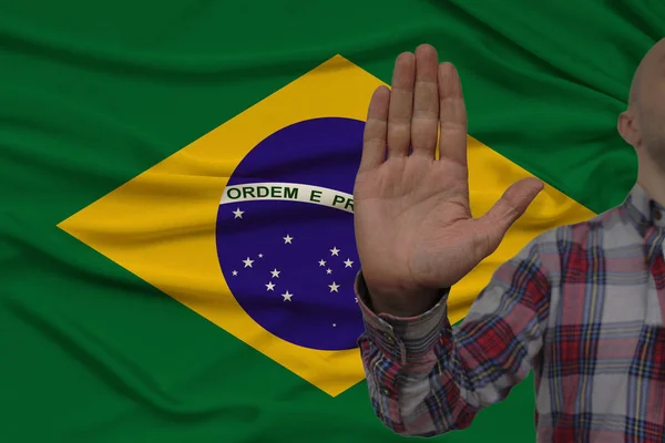 Männliche Hand mit einer Geste des Protests, Eide vor dem Hintergrund einer seidenen Nationalflagge, das Konzept der Verweigerung und des Verbots und des Verbots, Großaufnahme, Kopierraum — Stockfoto