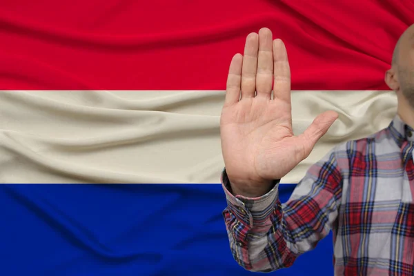 Mão masculina com gesto de protesto, juramentos contra o pano de fundo de uma bandeira nacional de seda, o conceito de negação e proibição e proibição, close-up, espaço de cópia — Fotografia de Stock