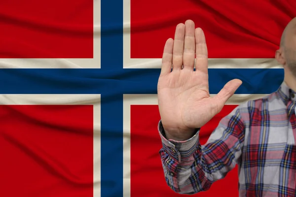 Mężczyzna ręka z gestem protestu, przysięgi na tle jedwabiu narodowej flagi Norwegii, pojęcie odmowy i zakaz i zakaz, zbliżenie, przestrzeń kopiowania — Zdjęcie stockowe