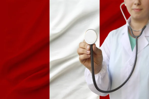 Fotografía parcial de una doctora, enfermera con un estetoscopio en uniforme en el fondo de la bandera nacional del estado del Perú, concepto de atención médica y seguro en el país — Foto de Stock