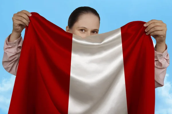 Mladá dívka drží v obou rukou národní vlajku Peru na krásném lesklém hedvábí proti modrému nebi, státní koncepci, cestování, imigraci, horizontální, těsné, kopírovací místo — Stock fotografie