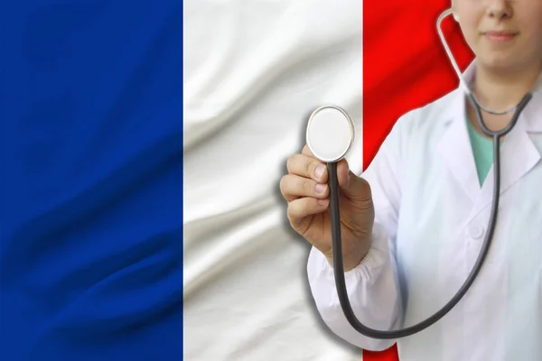 partial photograph of a doctor���s girl, a nurse with a stethoscope in uniform against the background of the colored national flag of the United Kingdom, a concept of medical care and insurance in the