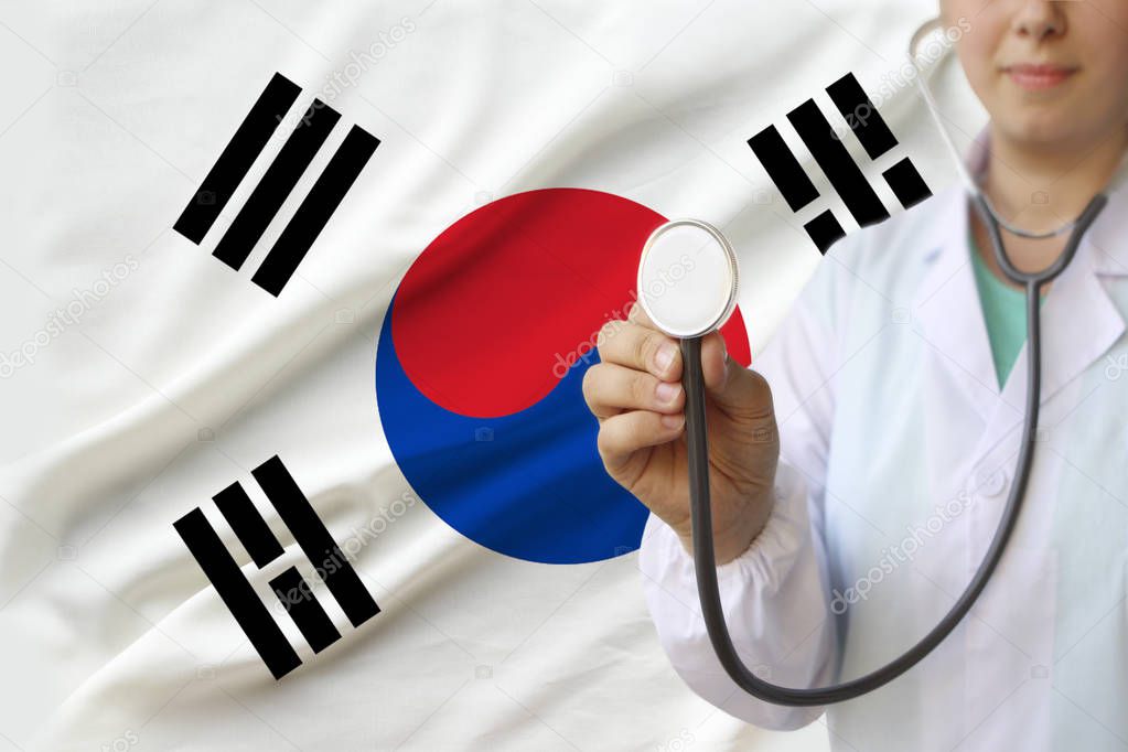 partial photo of a girl doctor, nurse with a stethoscope in uniform against the background of the national flag of the state of South Korea, the concept of medical care and insurance in the country