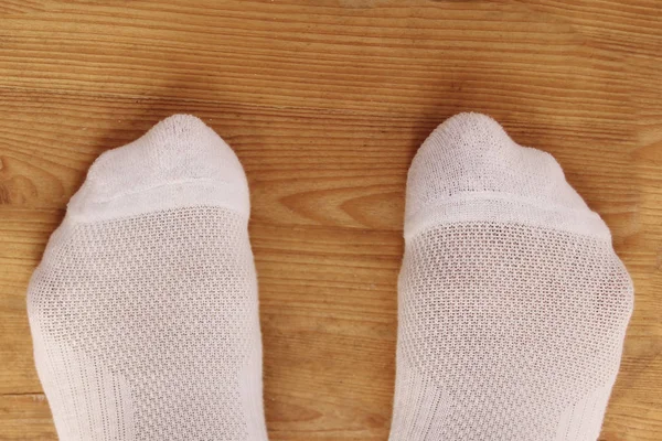 Женские ноги в белых носках на деревянном полу, крупным планом, пространство для копирования — стоковое фото