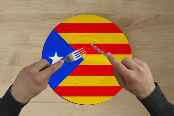 Χέρια με μαχαιροπίρουνα σε ένα πιάτο με την Κρατική εθνική σημαία της Καταλωνίας, αντιγραφή χώρου — Φωτογραφία Αρχείου
