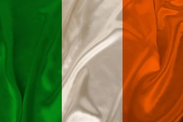 photo of the national flag of Ireland on a luxurious texture of satin, silk with waves, folds and highlights, closeup, copy space, travel concept, economy and state policy, illustration