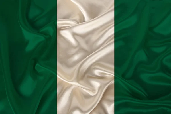 Foto de la bandera nacional de Nigeria en una textura lujosa de satén, seda con olas, pliegues y reflejos, primer plano, espacio para copiar, concepto de viaje, economía y política de estado, ilustración — Foto de Stock