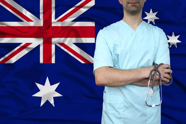 male doctor in uniform professional clothes with a stethoscope stands against the background of the national flag, the concept of the country's health and medical insurance, close-up, copy space