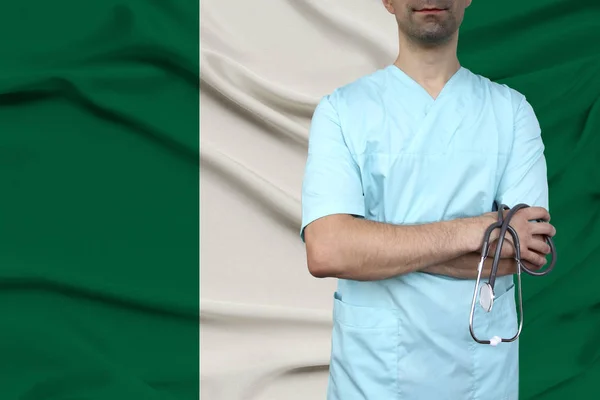 Médico en uniforme con estetoscopio se encuentra en el fondo de la bandera nacional, el concepto de salud y seguro médico del país, primer plano, espacio de copia — Foto de Stock