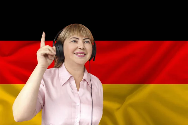 Femme dans les écouteurs sur le fond du drapeau national de l'Allemagne sur la soie brillante délicate, concept de diffusion libre, musique, nouvelles, podcast, horizontal, gros plan, espace de copie — Photo