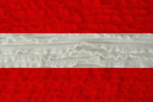 Schöne Nationalflagge des Landes Österreich auf einem weichen Hintergrund aus gestrickter Wolle mit kleinen Volants aus Leinen — Stockfoto